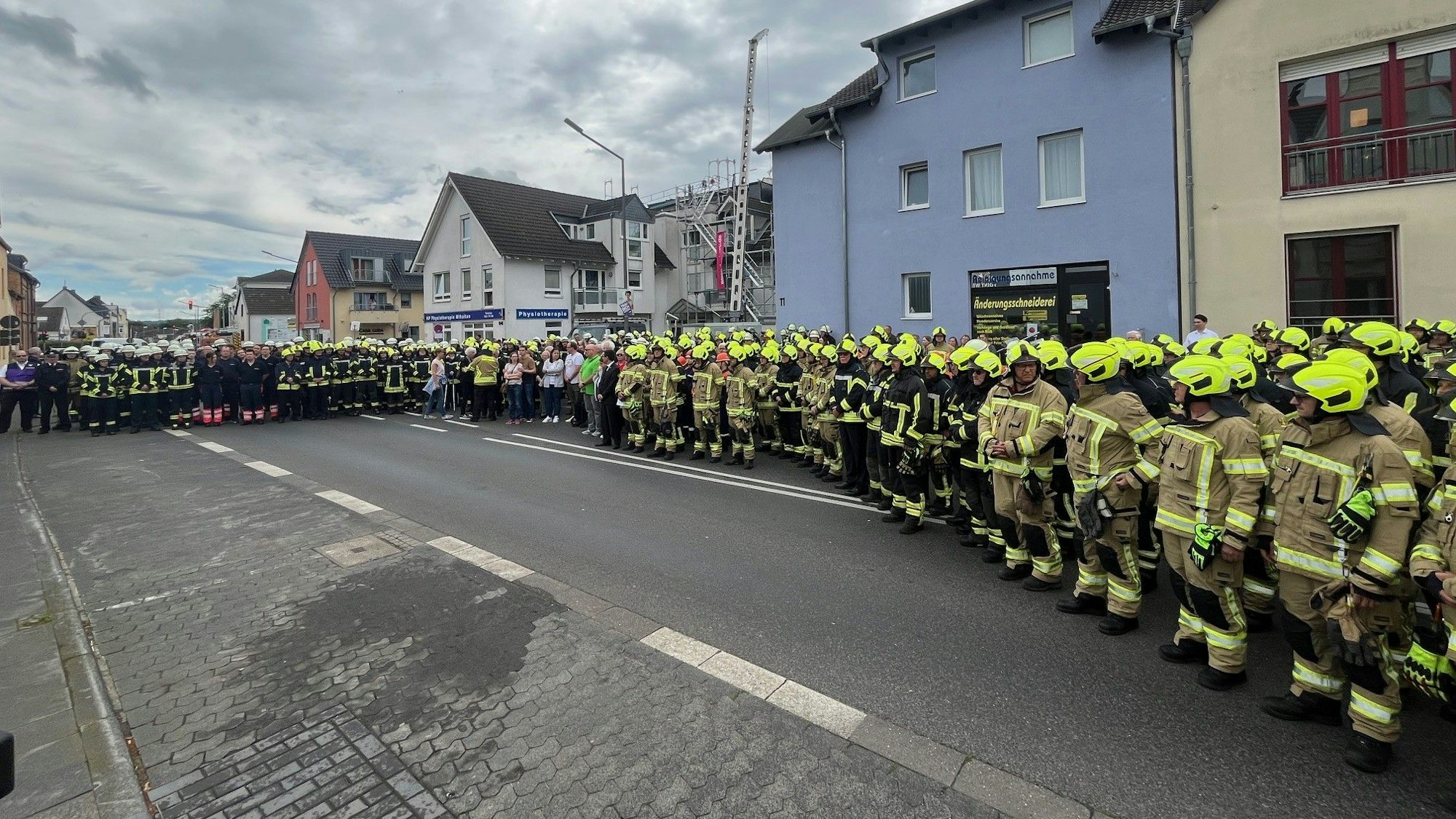 Viele Menschen, darunter hunderte Feuerwehrleute stehen auf einer Straße.