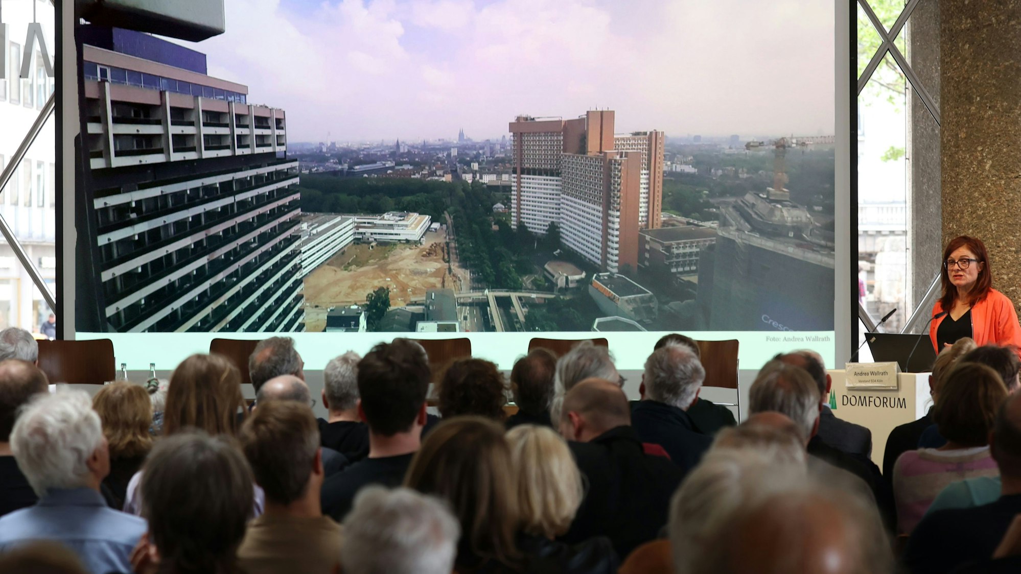 Zu sehen ist eine Frau, die vor Publikum spricht.