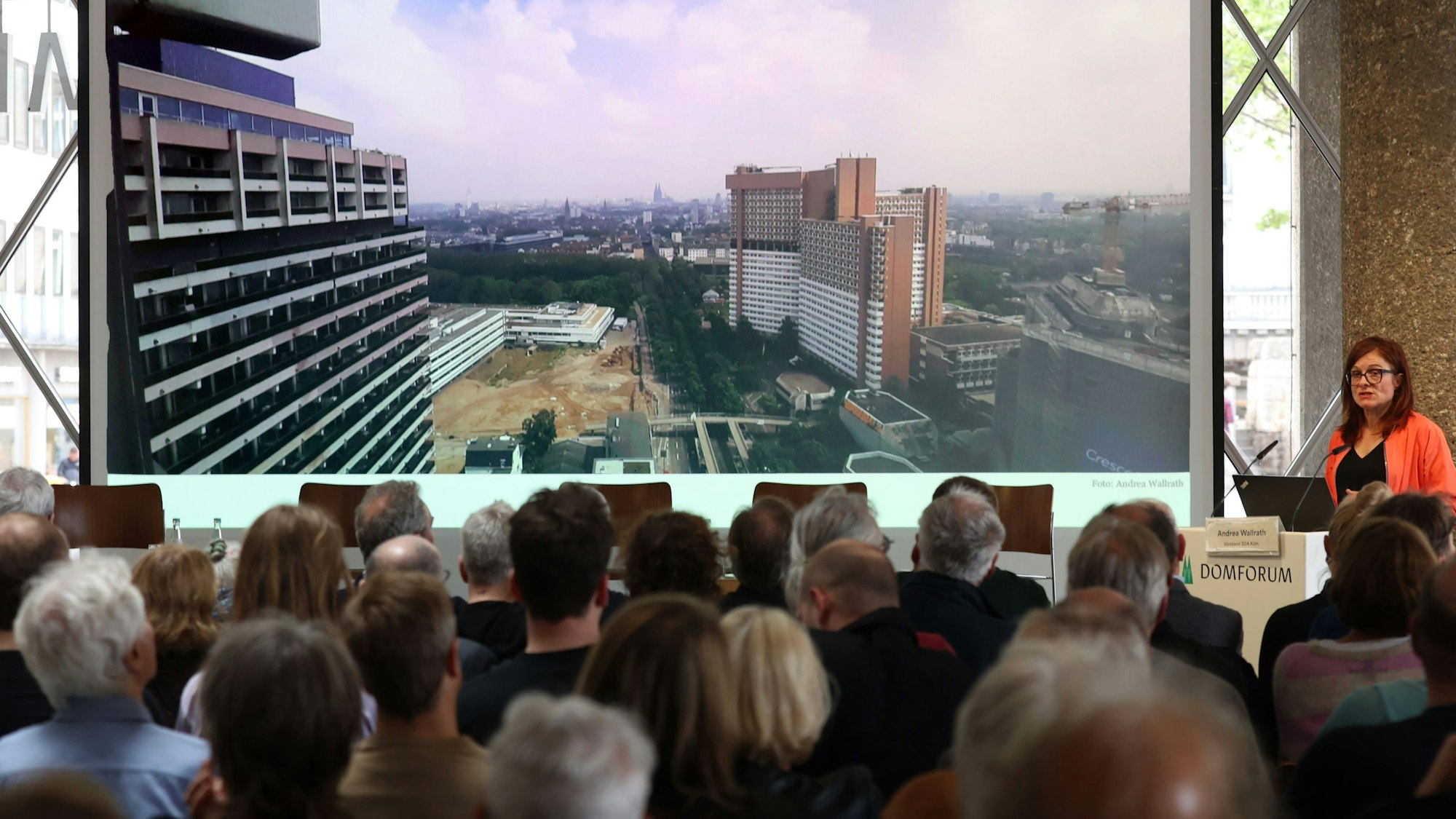 Zu sehen ist eine Frau, die vor Publikum spricht.