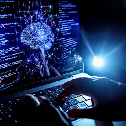 Auf einem Bildschirm sind ein Gehirn und mehrere Algorithmen abgebildet.