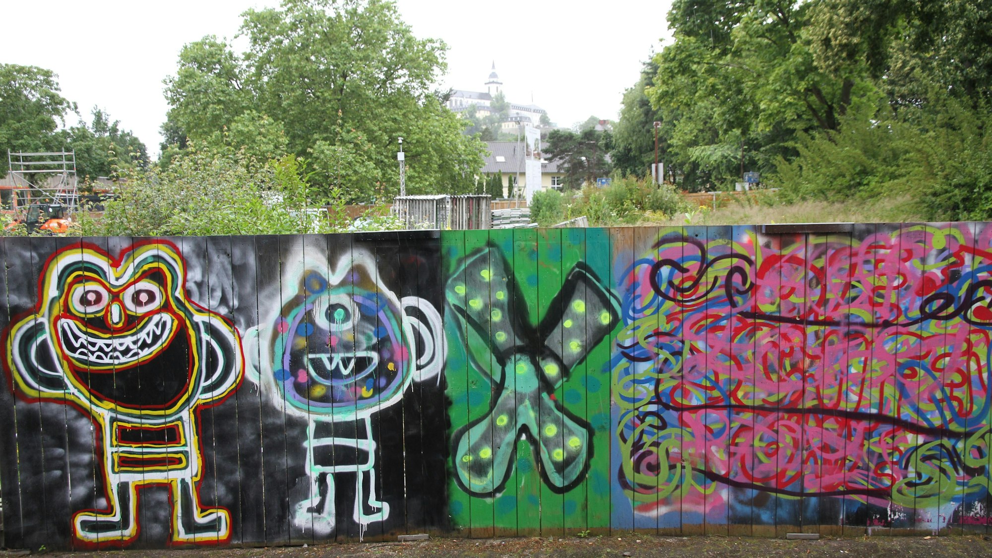 Graffiti auf einem Bauzaun aus Holzbrettern