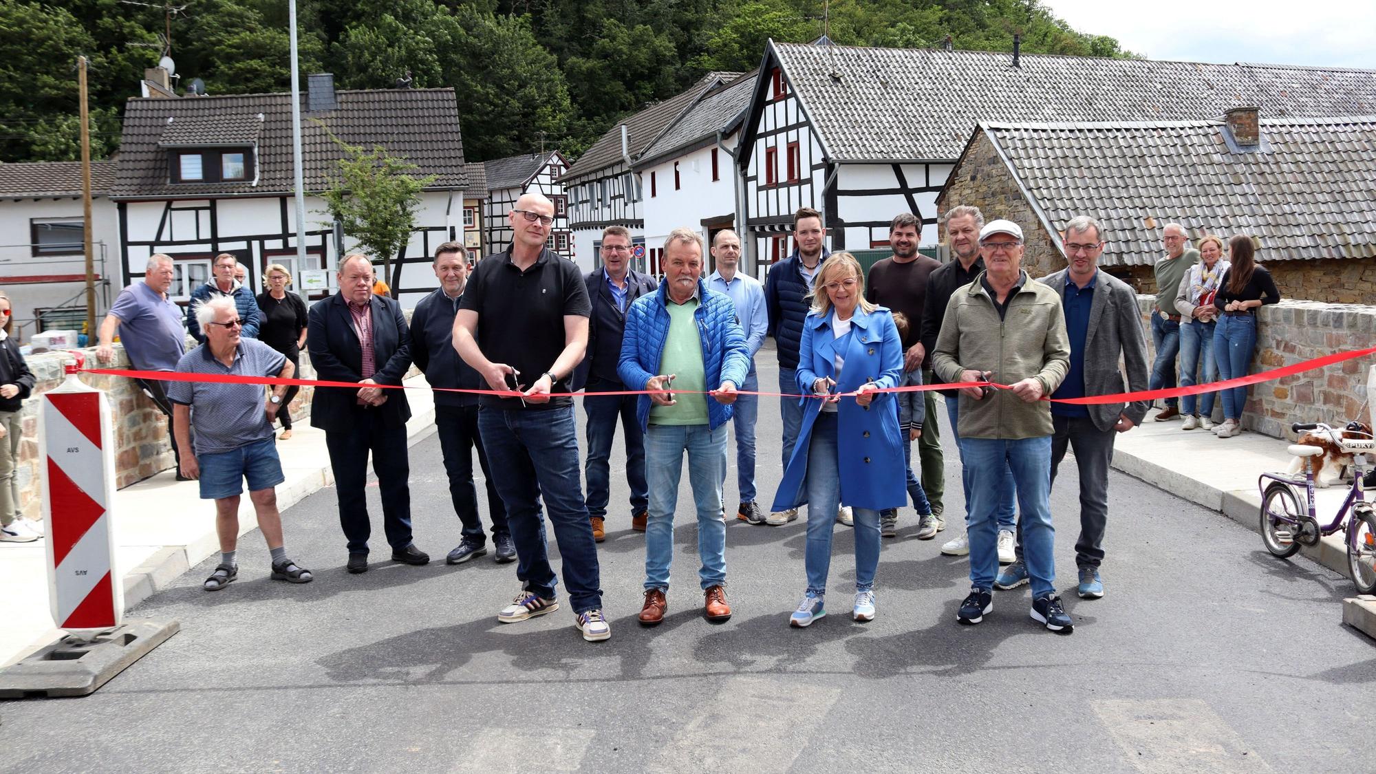 Die Bürgermeisterin und drei Politiker mit Scheren in den Händen durchtrennen auf einer Brücke ein rotes Band. Im Hintergrund stehen Menschen, die zuschauen.