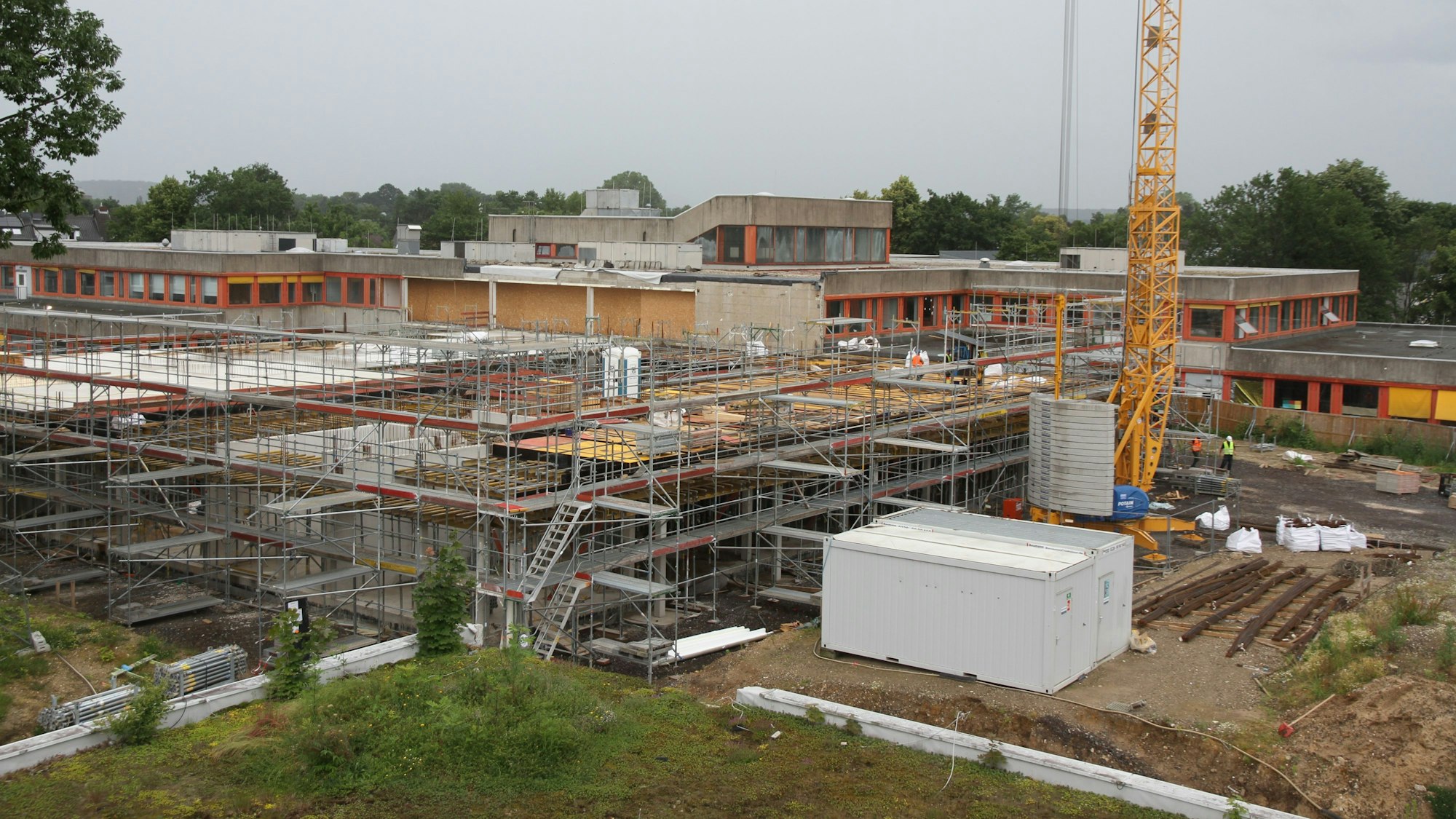 Blick auf eine Großbaustelle, im Hintergrund ein Schulzentrum