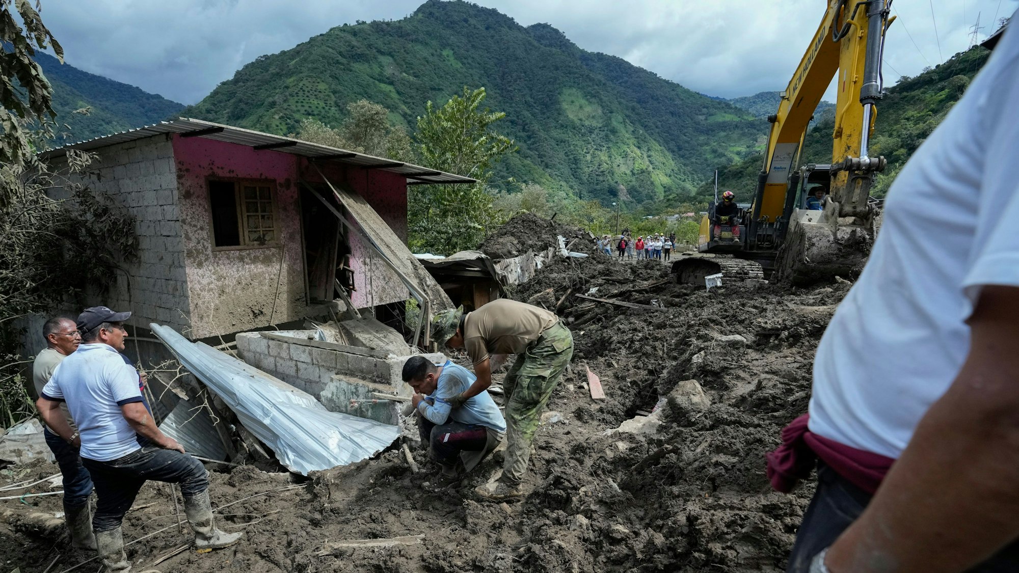 Ein kniender Bewohner reagiert, nachdem Erdrutsche sein Haus beschädigt haben.