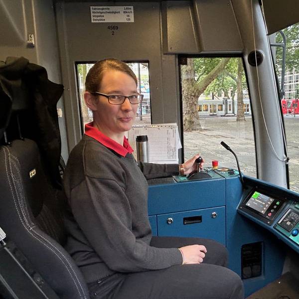 Von der Orgelbauerin zur Straßenbahnfahrerin: Astrid Sadra fährt seit drei Jahren für die Kölner Verkehrs-Betriebe. Hier ist sie in einer Fahrerkabine zu sehen. Sie lächelt in die Kamera