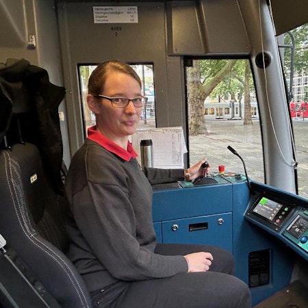 Von der Orgelbauerin zur Straßenbahnfahrerin: Astrid Sadra fährt seit drei Jahren für die Kölner Verkehrs-Betriebe. Hier ist sie in einer Fahrerkabine zu sehen. Sie lächelt in die Kamera