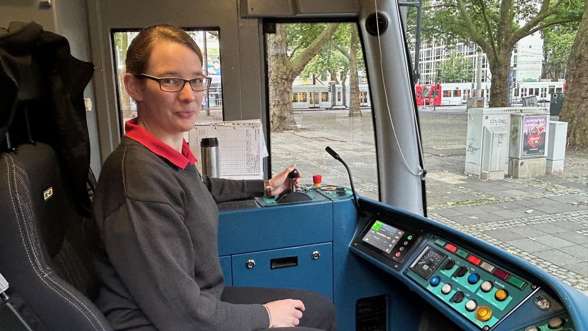 Von der Orgelbauerin zur Straßenbahnfahrerin: Astrid Sadra fährt seit drei Jahren für die Kölner Verkehrs-Betriebe. Hier ist sie in einer Fahrerkabine zu sehen. Sie lächelt in die Kamera