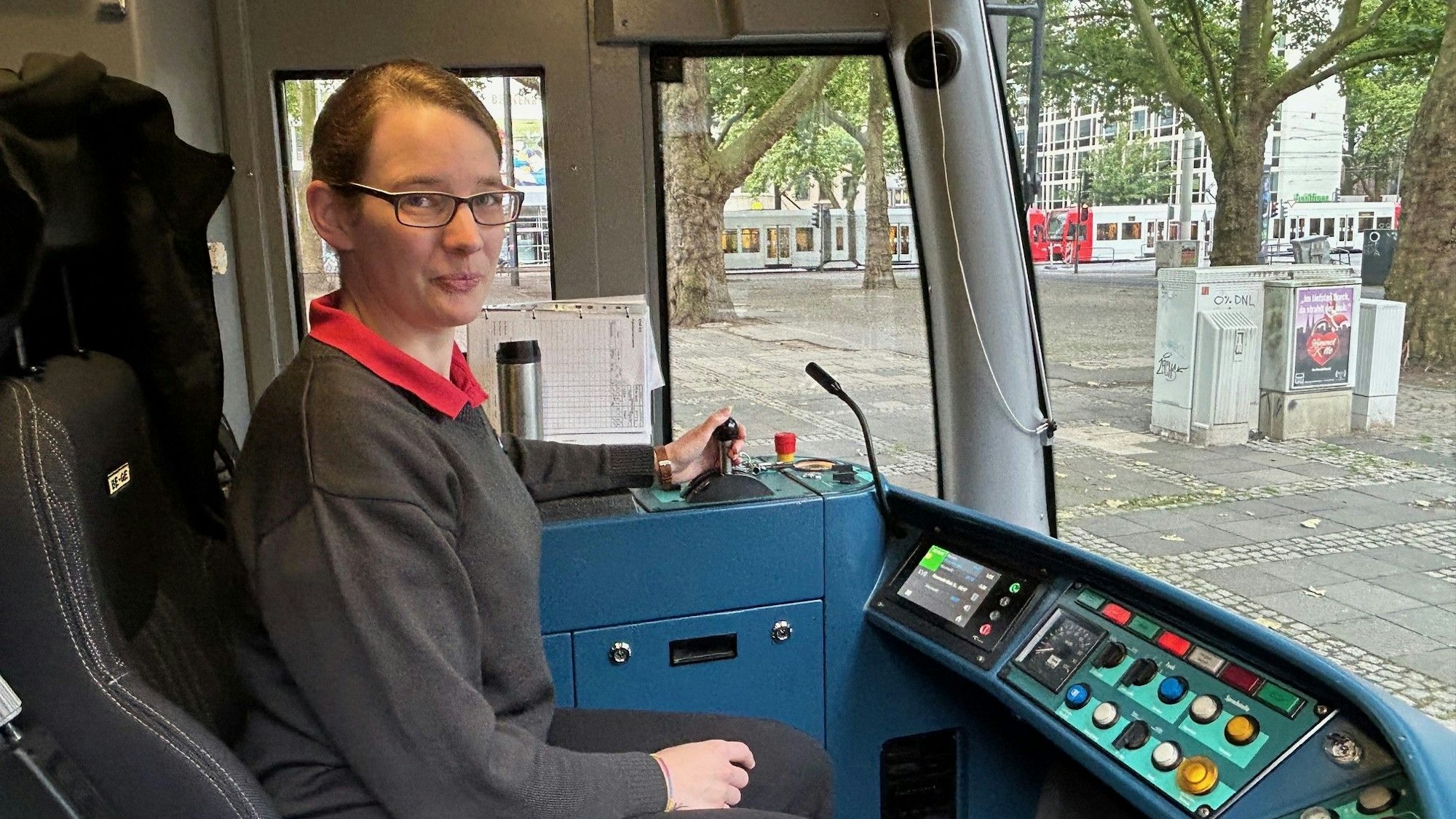 Von der Orgelbauerin zur Straßenbahnfahrerin: Astrid Sadra fährt seit drei Jahren für die Kölner Verkehrs-Betriebe. Hier ist sie in einer Fahrerkabine zu sehen. Sie lächelt in die Kamera