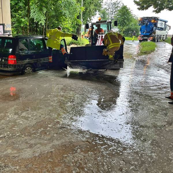 Einsatzkräfte der Feuerwehr auf einem Fahrzeug, das in einer Unterführung im Wasser steht.