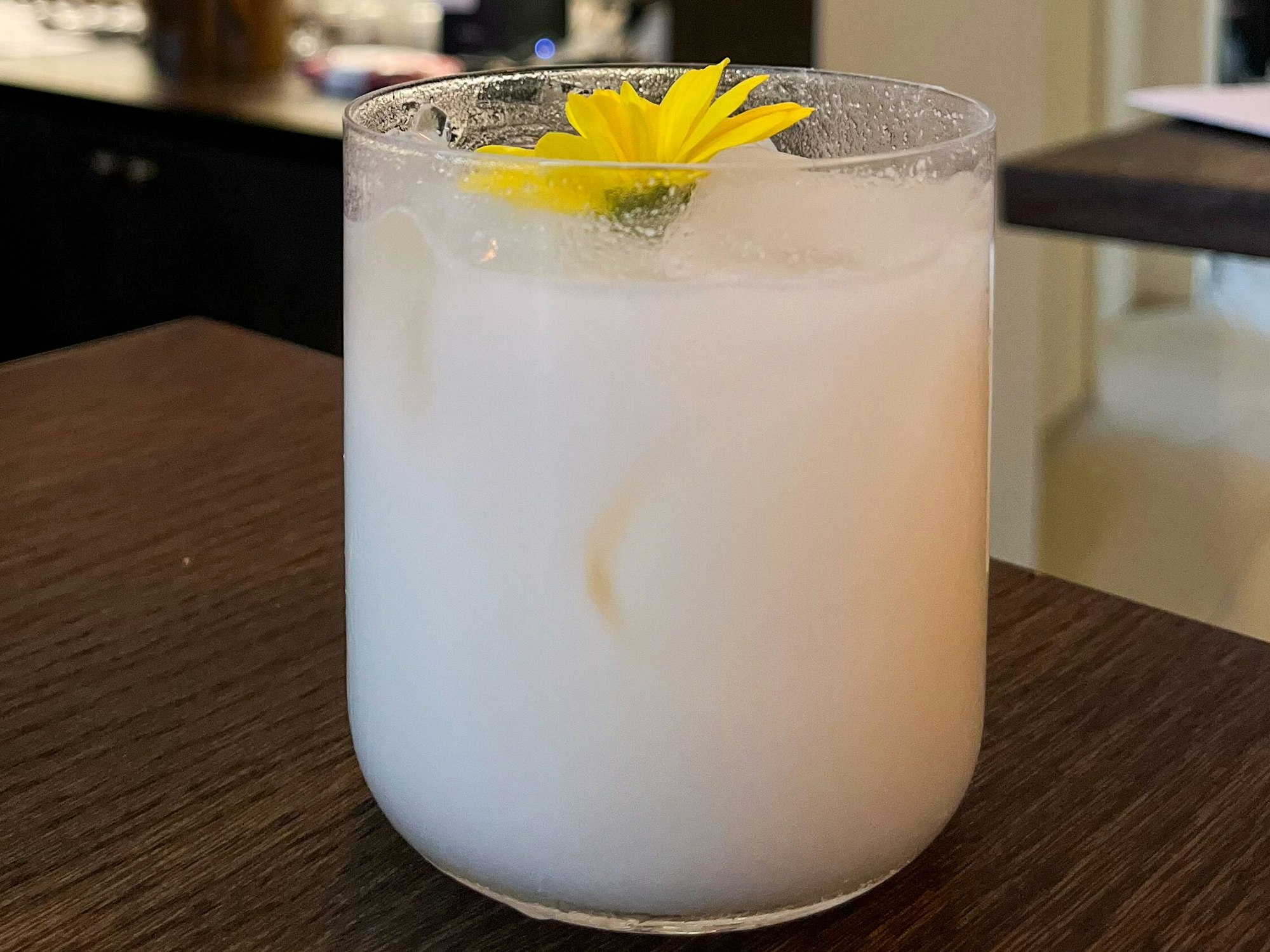 Glas mit weißem Cocktail steht auf einem Tisch