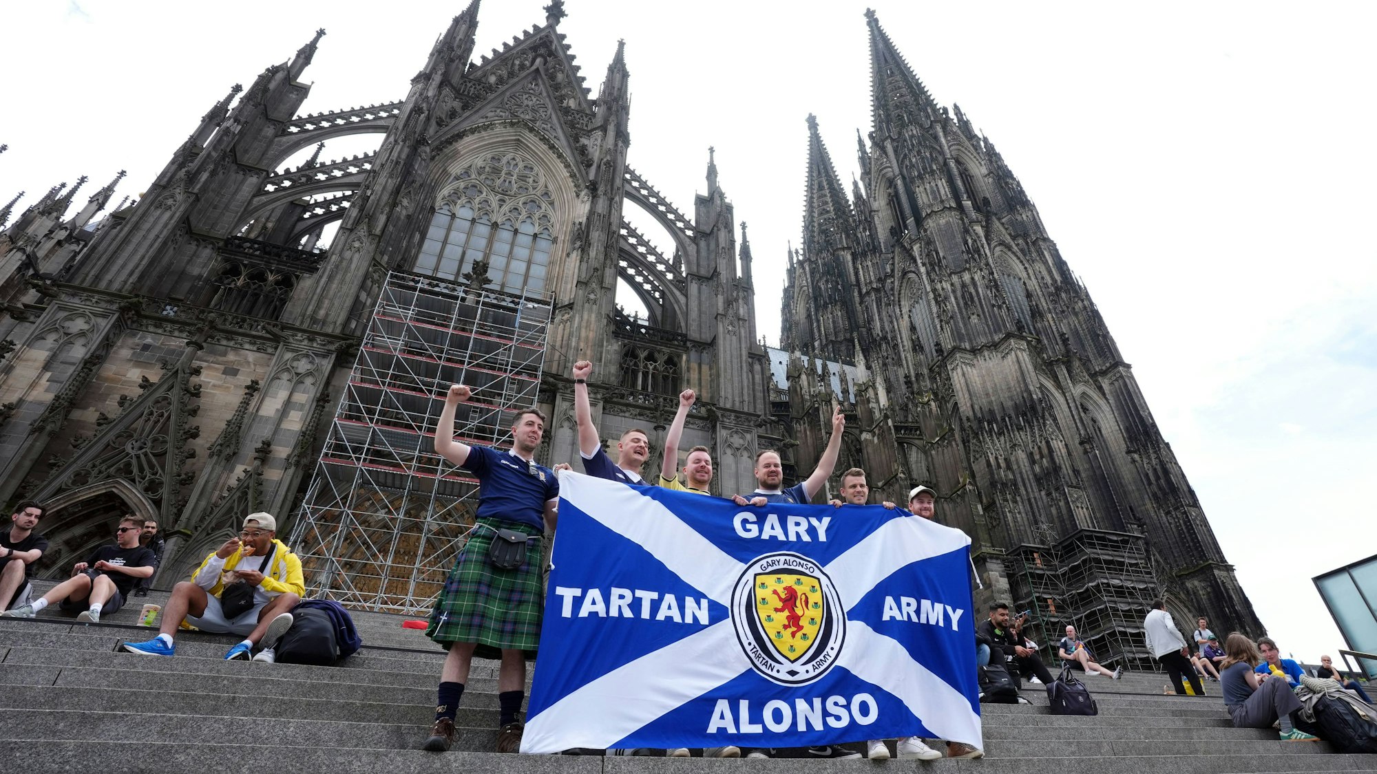 Mehrere schottische Anhänger stehen vor dem Kölner Dom und halten eine Flagge der „Tartan Army“ vor sich. Ein schottischer Fan ist kurz vor dem zweiten Gruppenspiel der Schotten gegen die Schweiz plötzlich gestorben. (Symbolbild)