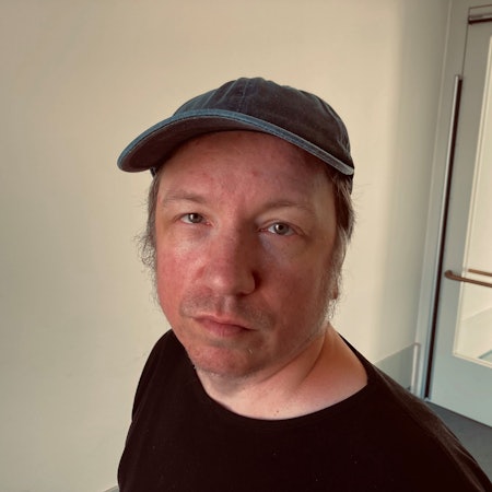 Der Duisburger Dirk Hähnel reparierte in einer Werkstatt für Menschen mit Behinderungen Computerbildschirme – und erhielt dafür 1,35 Euro pro Stunde. Er ist im Porträt zu sehen, trägt eine Baseballcap und schaut zweifelnd-lächelnd in die Kamera.