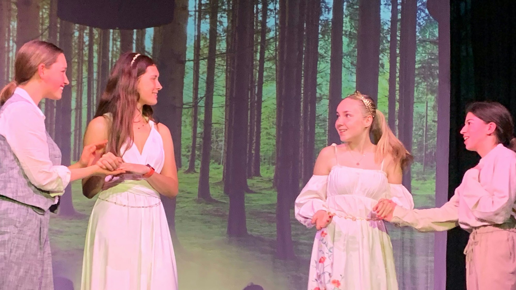 Vier Schülerinnen stehen im Wald, der per Fotoprojektion zum Bühnenbild wurde.