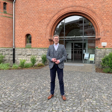 Ein Mann steht vor dem Eingangsportal eines Kirchengebäudes.