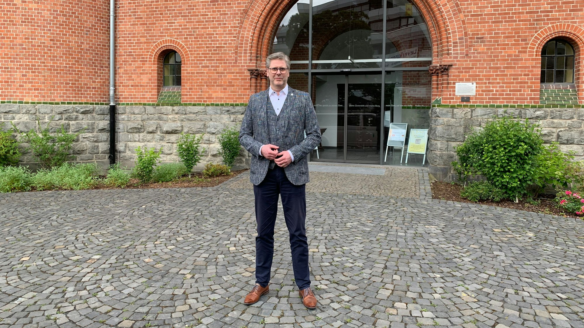 Ein Mann steht vor dem Eingangsportal eines Kirchengebäudes.