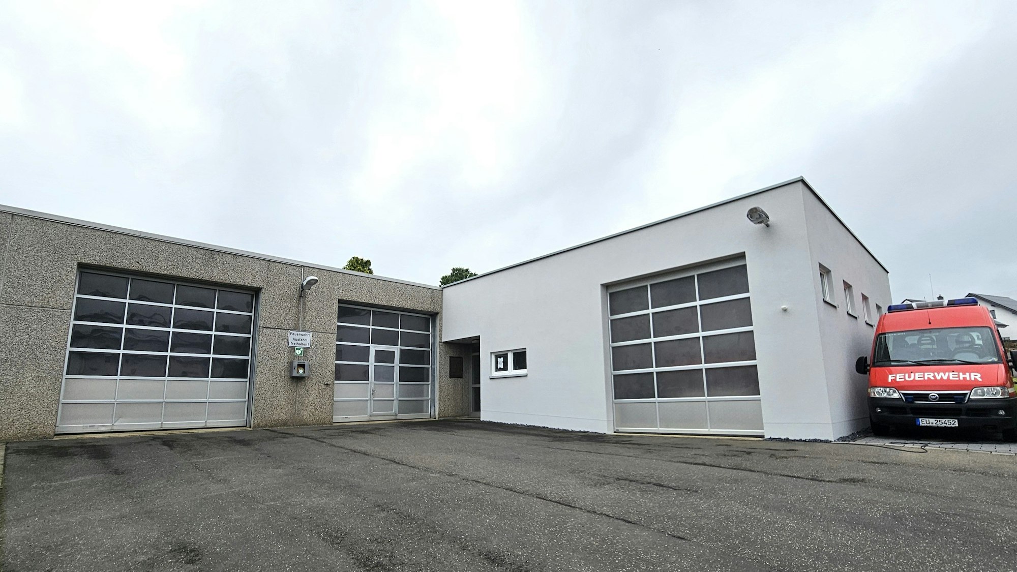 Blick auf das Gerätehaus, neben dem ein Feuerwehrwagen steht.