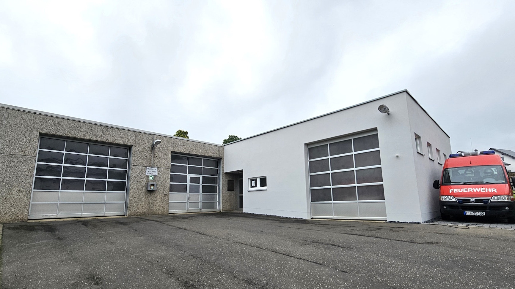 Blick auf das Gerätehaus, neben dem ein Feuerwehrwagen steht.