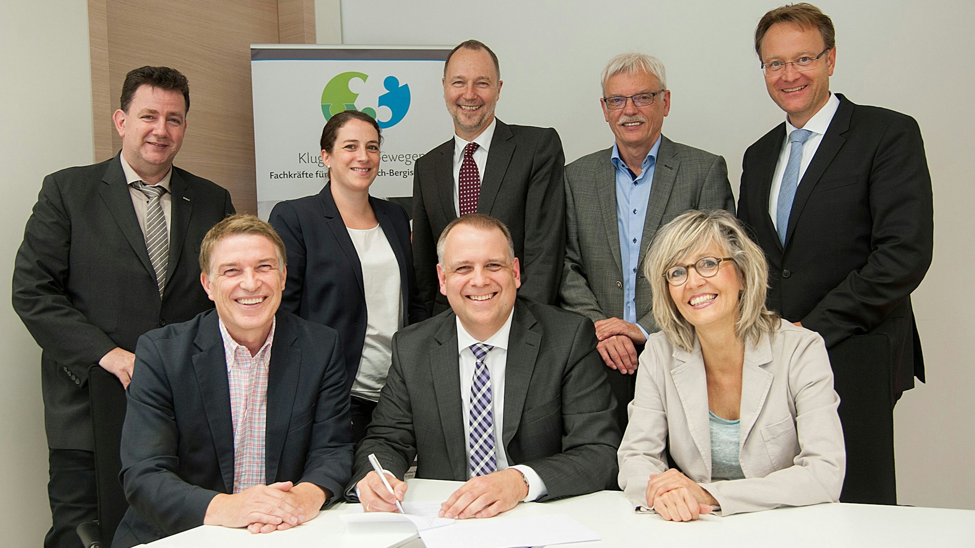 Menschen unterzeichnen eine Vereinbarung an einem Tisch.