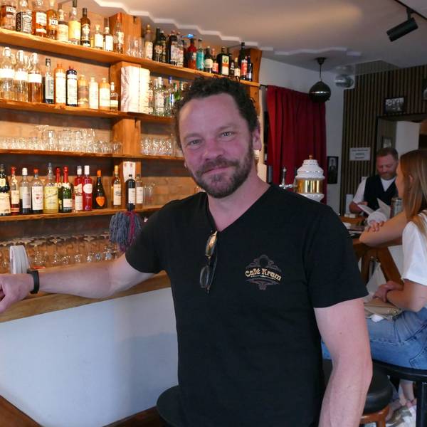 Ein Mann in schwarzem T-Shirt sitzt vor seiner Theke.