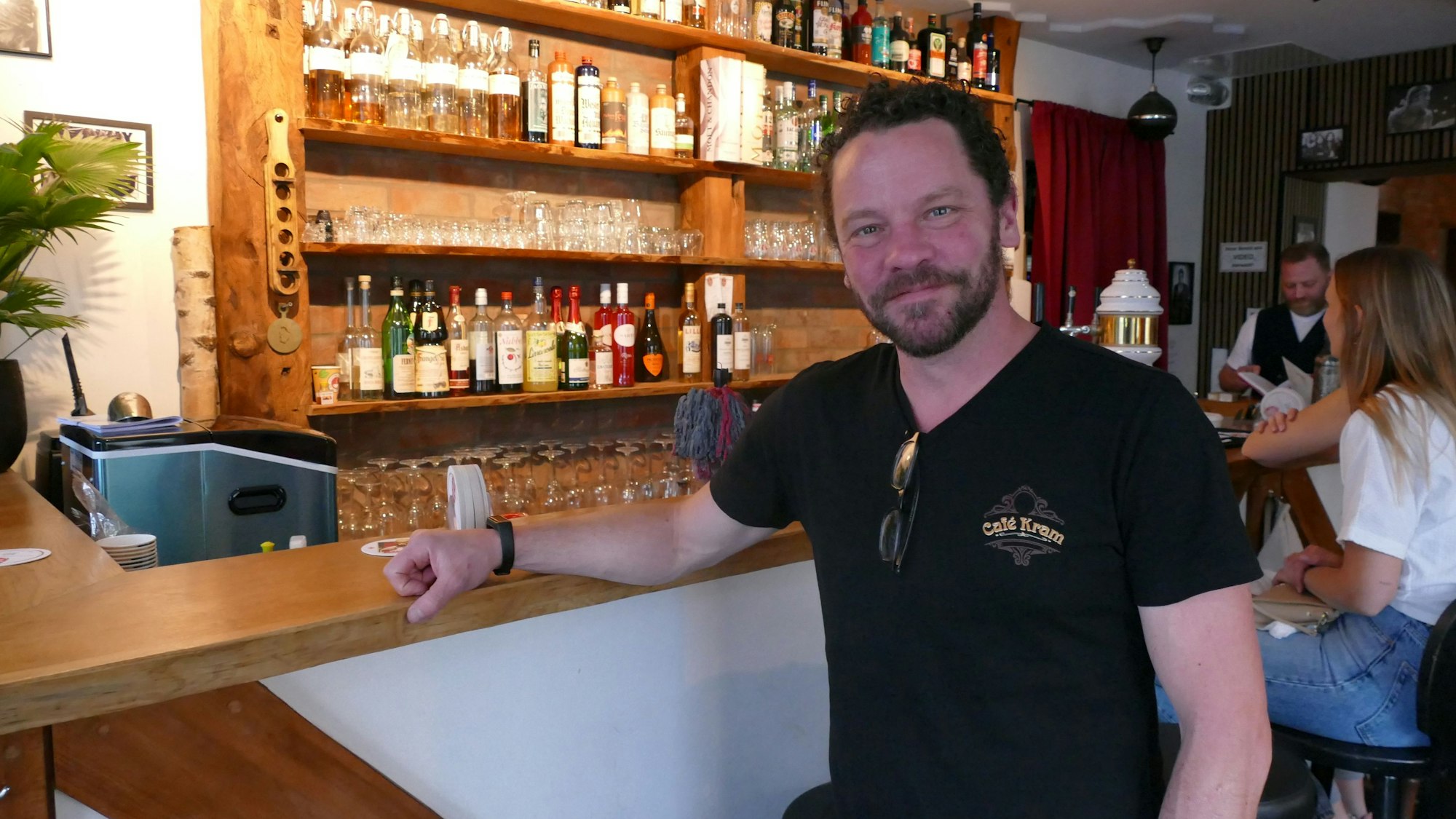 Ein Mann in schwarzem T-Shirt sitzt vor seiner Theke.