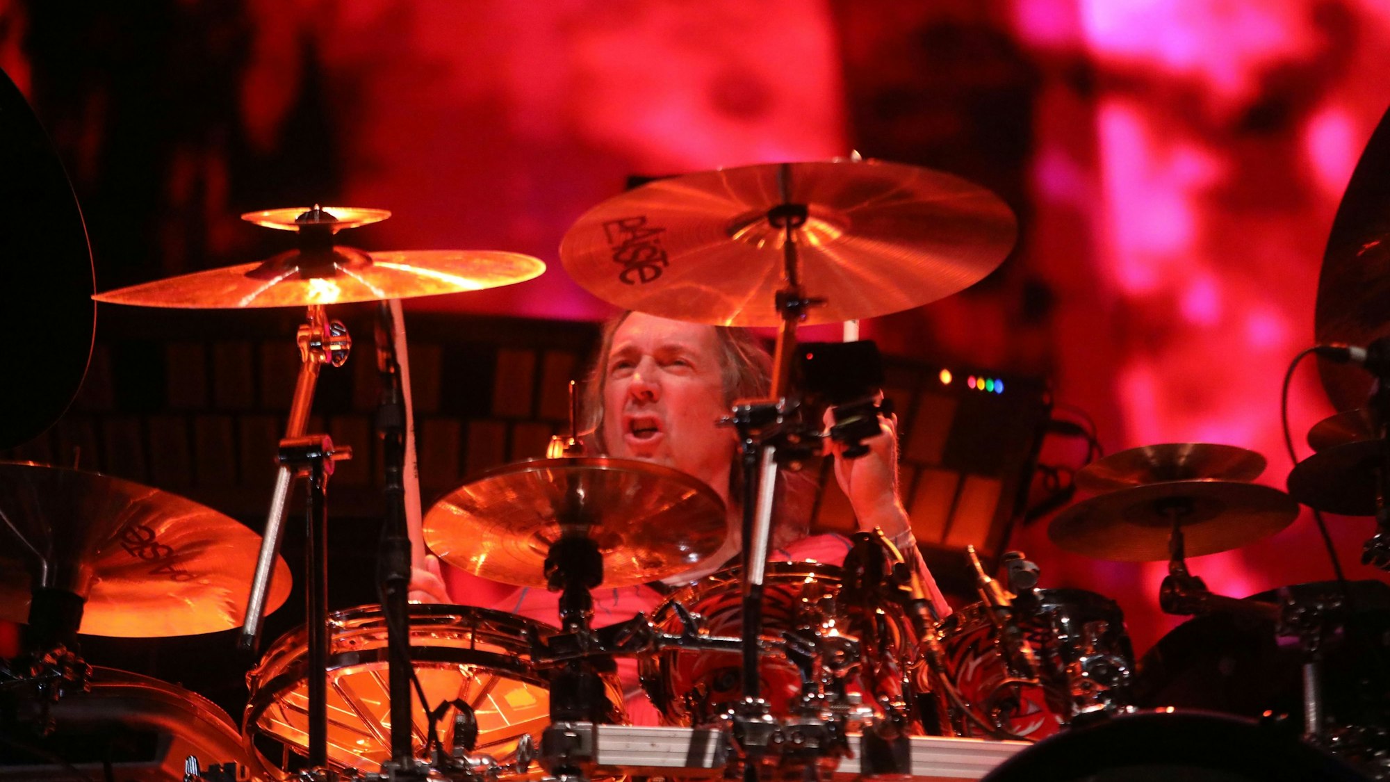 Der Schlagzeuger Danny Carey von Tool sitzt an seinem Arbeitsgerät. Im Hintergrund sieht man schemenhaft die Visualisierung der Musik der Band.