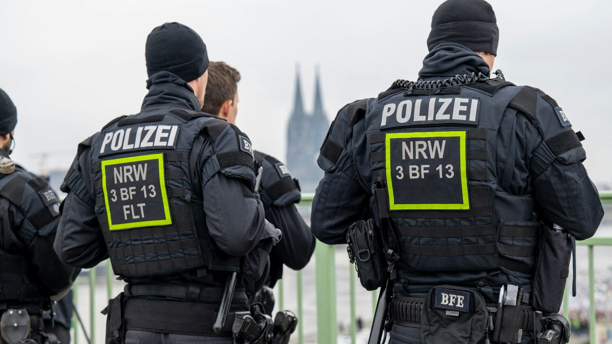 Polizeibeamte sind von hinten vor einer Absperrung zu sehen. Im Hintergrund sind die Domspitzen zu erkennen.