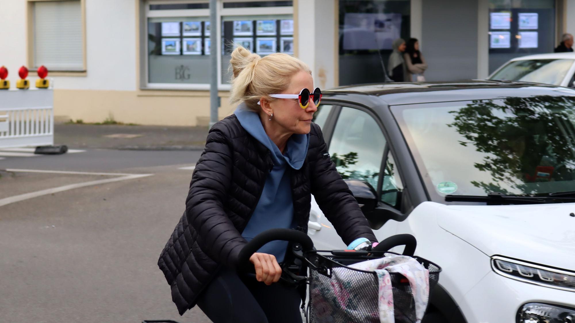 Eine Frau auf einem Fahrrad trägt eine schwarz-rot-goldene Brille.