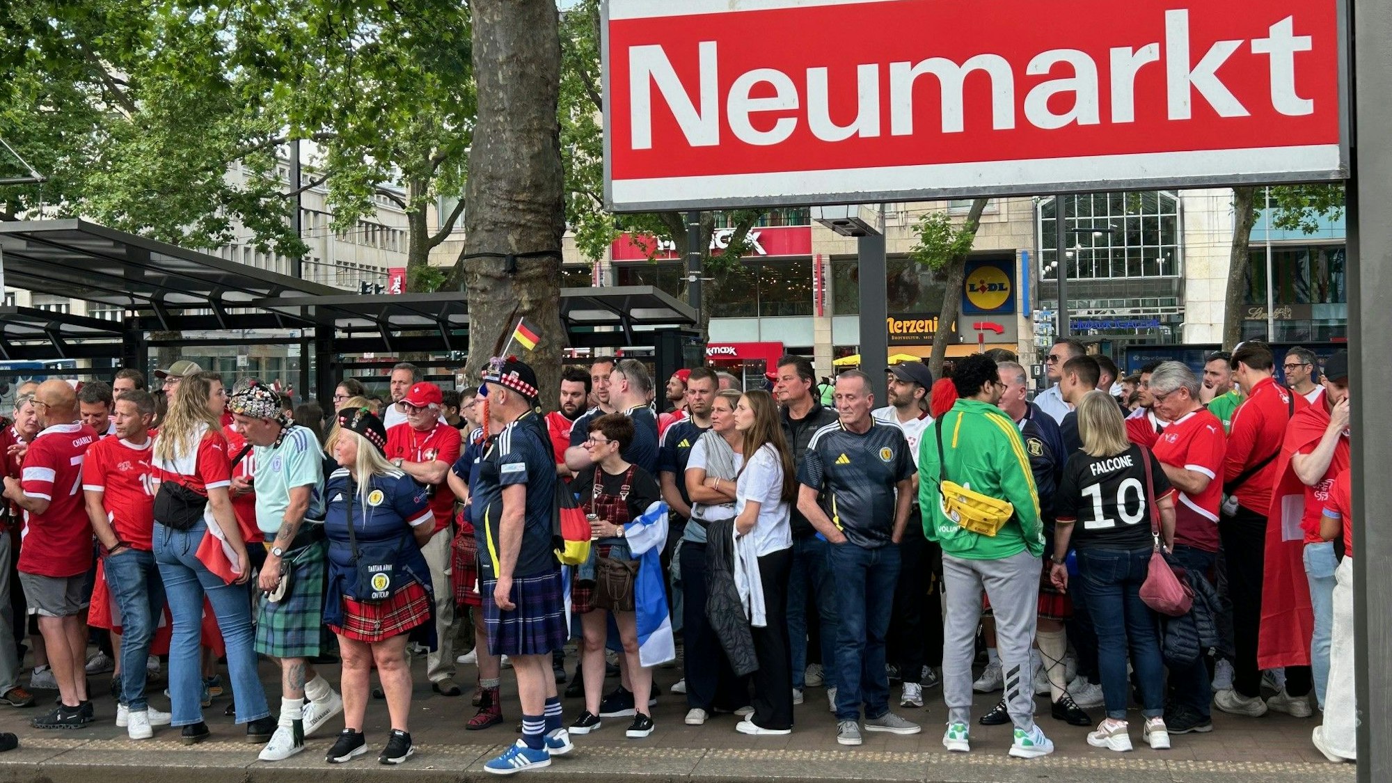 Fußballfans aus Schottland und der Schweiz warten am Donnerstag vor dem Spiel im Rhein-Energie-Stadion am Neumarkt auf die Straßenbahn.