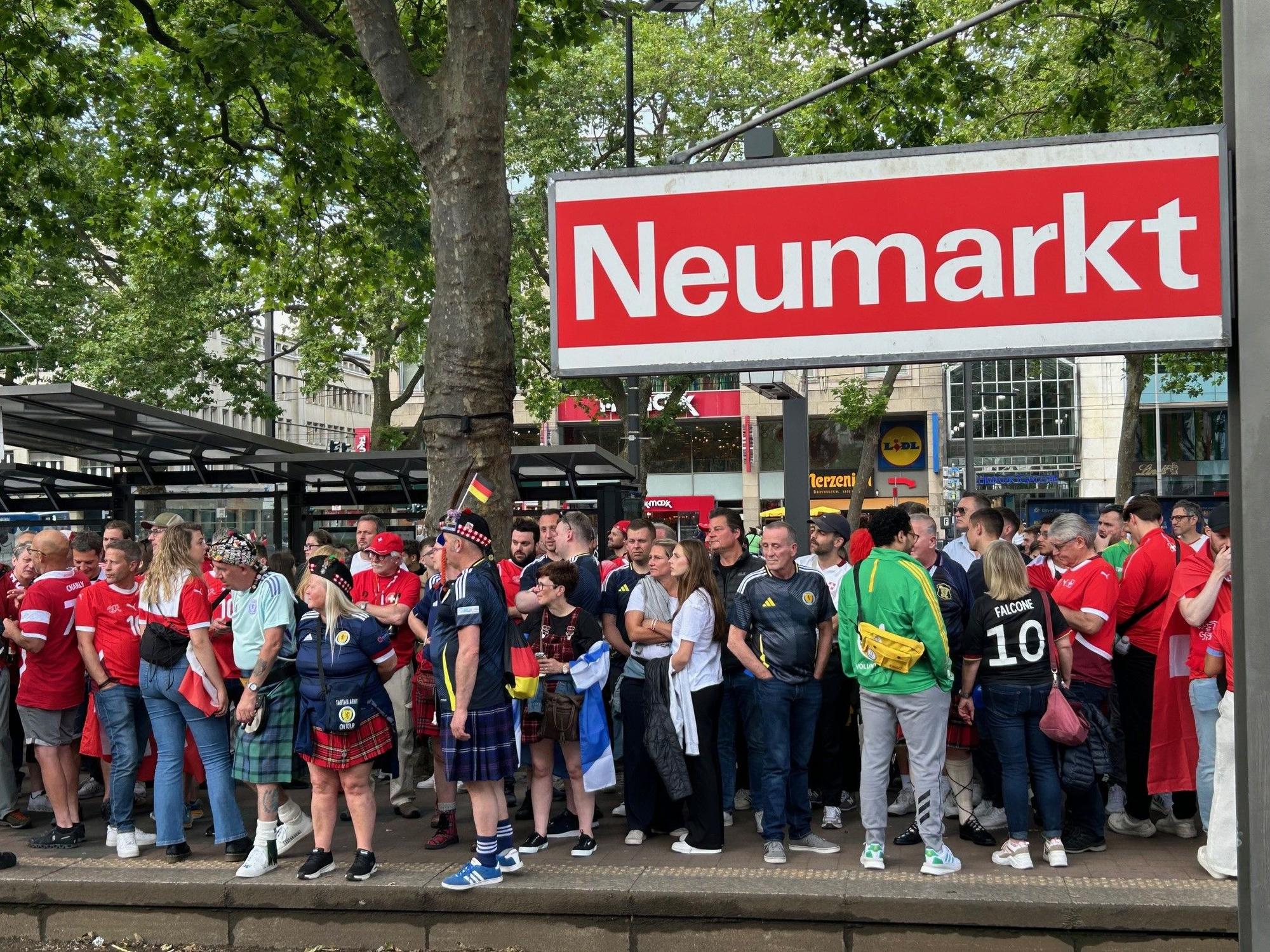 Fußballfans aus Schottland und der Schweiz warten am Donnerstag vor dem Spiel im Rhein-Energie-Stadion am Neumarkt auf die Straßenbahn.