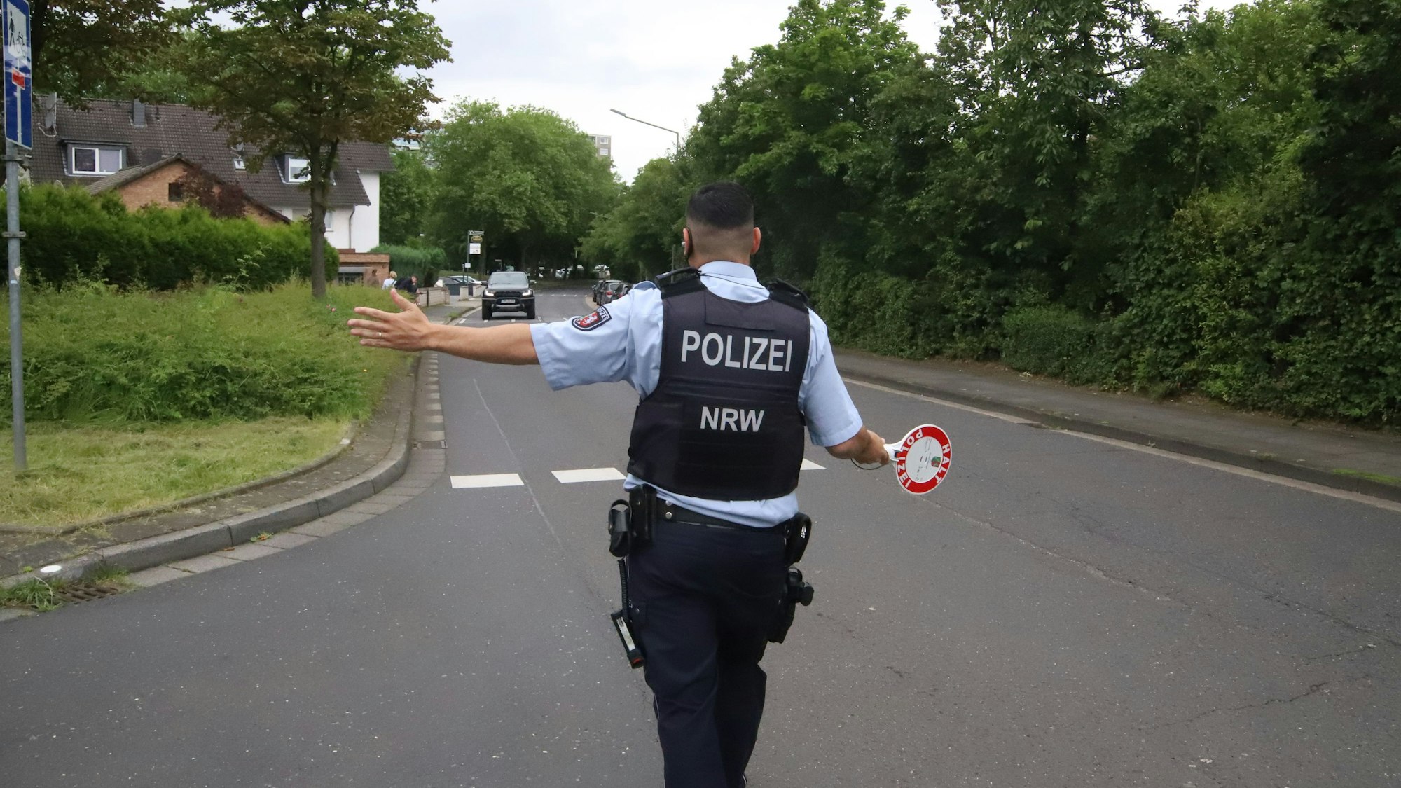 Ein Polizist mit einer Kelle in der Hand winkt einen Autofahrer heraus.