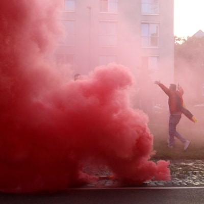 Eine rote Wolke ist auf dem Europaplatz zu sehen. Ein Fan läuft jubelnd über den Platz, er ist von dem Rauch eingehüllt.