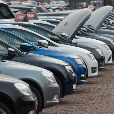 Neu- und Gebrauchtwagen stehen bei einem Autohändler nebeneinander.