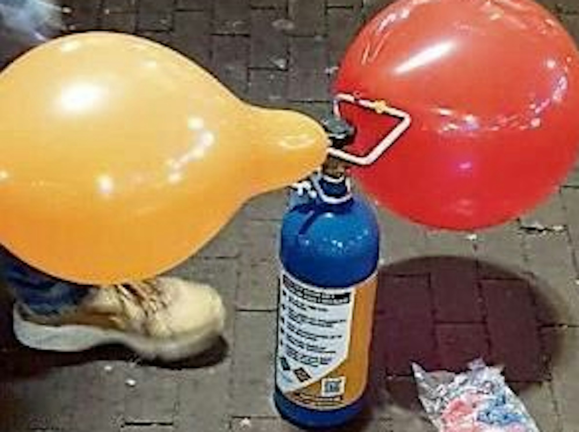 Das Bild zeigt eine Kartusche mit Lachgas und zwei Luftballons.