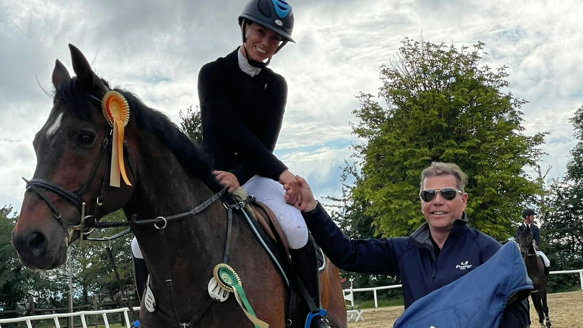 Die Siegerin eines Reitwettbewerbs sitz noch auf dem Pferd und bekommt ihren Preis vom Sponsor überreicht.