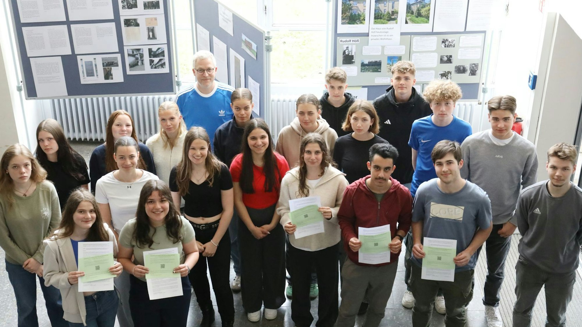 Eine Gruppe von Schülerinnen und Schülern steht vor den Stellwänden einer Ausstellung.