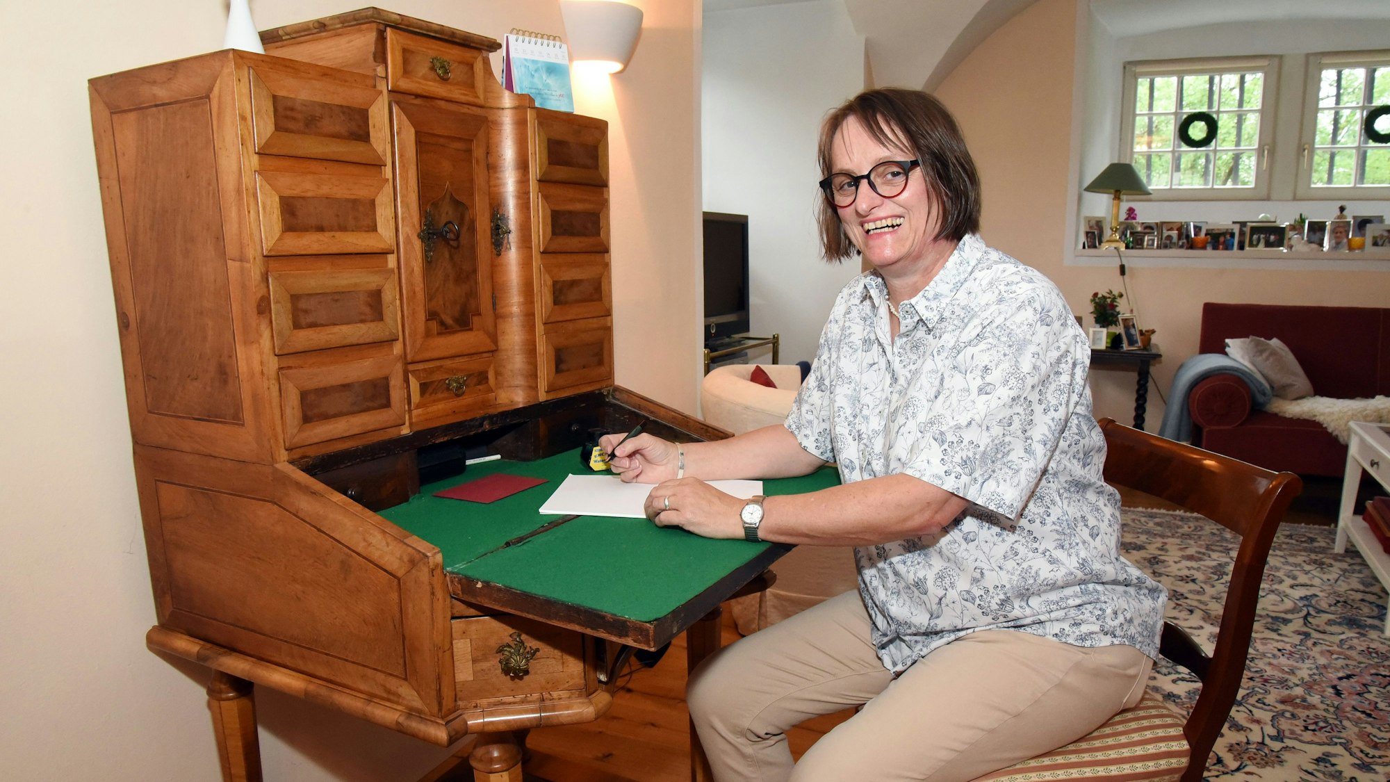 Lioba von Detten sitzt in in ihrer Wohnung in Schloss Ehreshoven bei Engelskirchen an einem Sekretär aus dem 19. Jahrhundert.