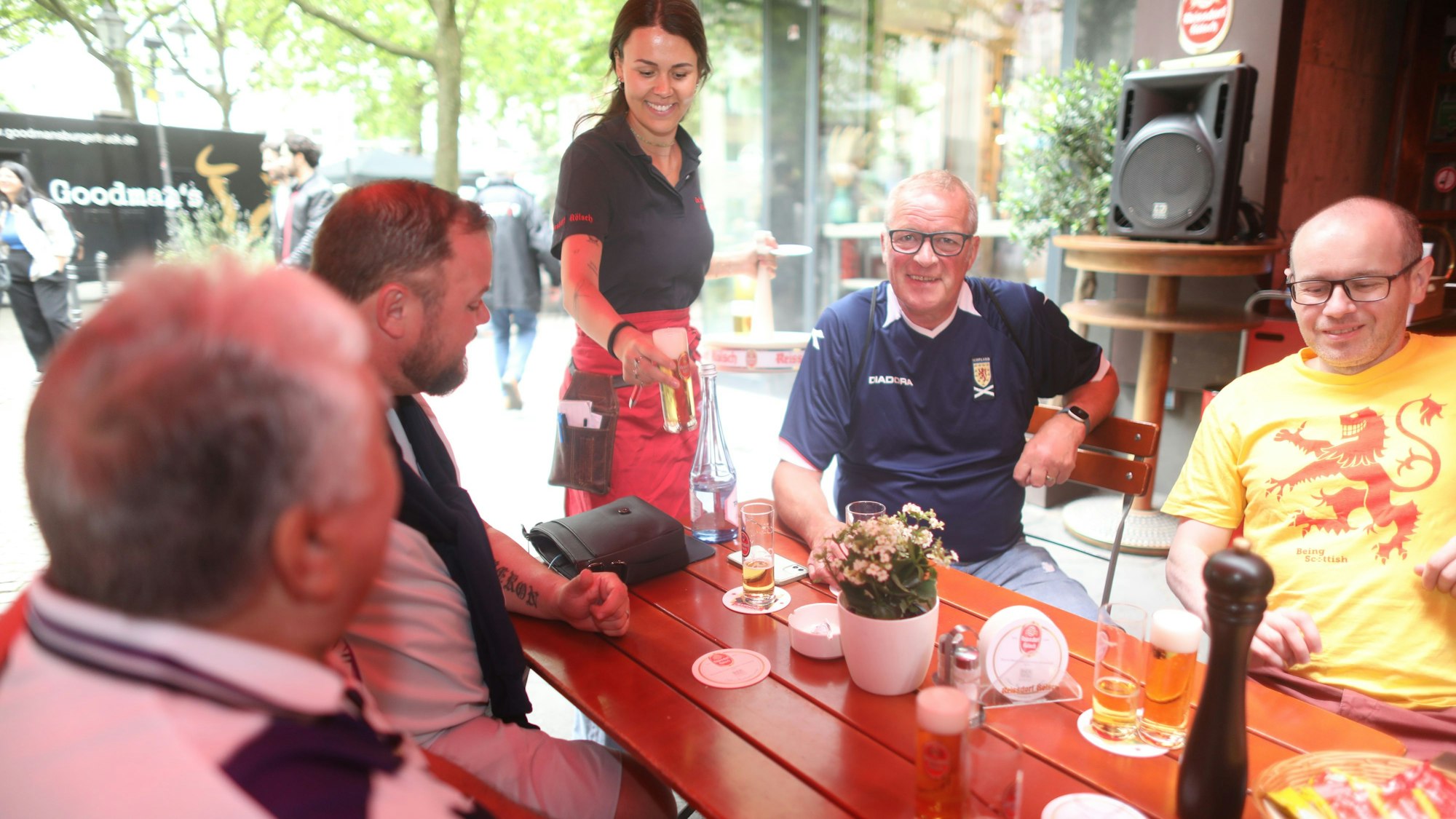 Schottische Fans und eine Kellnerin, die ihnen Kölsch bringt.