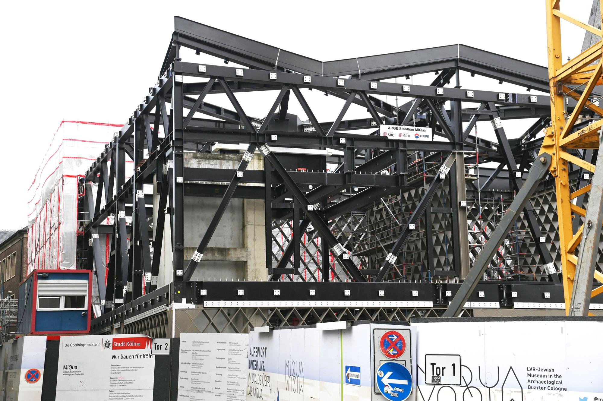 Die Baustelle des Jüdischen Museums in Köln, zu sehen mit einer großen, schwarzen Stahlträgerkonstruktion.