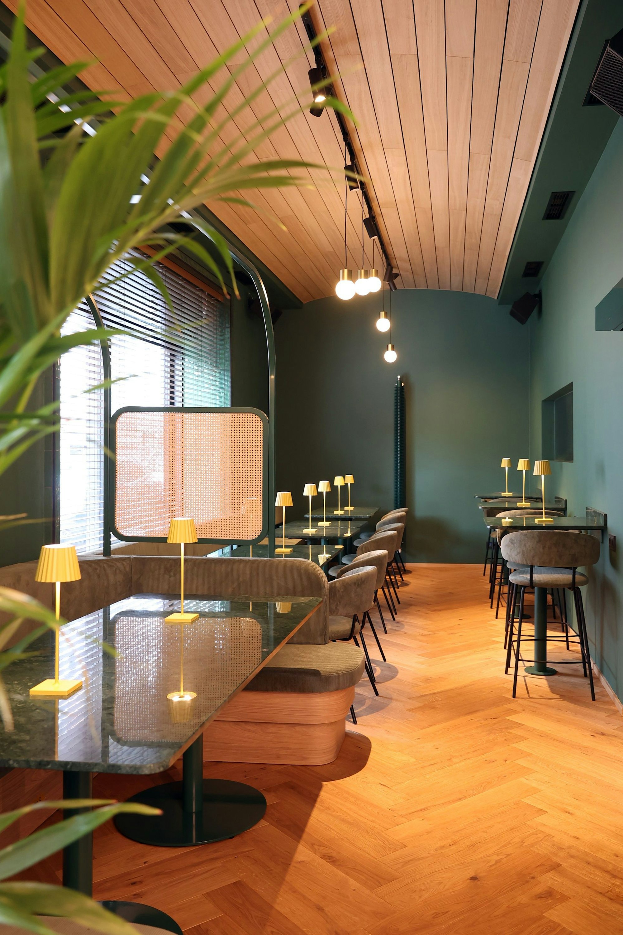 Blick in den Innenraum des Restaurants mit grünen Wänden, holzvertäfelter Decke und Holzboden.