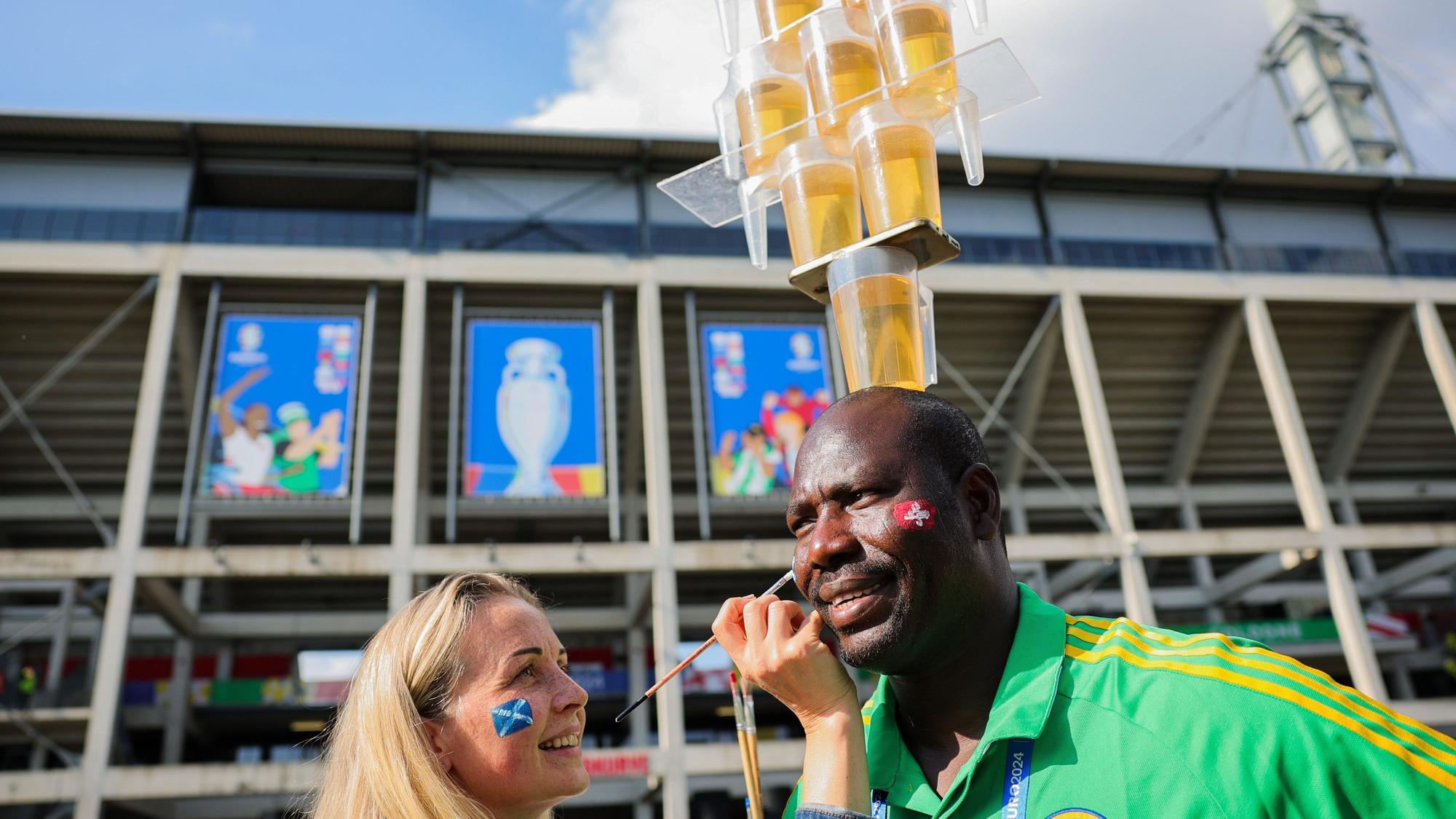 Lena aus der Ukraine malt Mohammed eine schottische Fahne auf die Wange.
