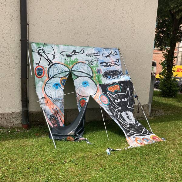 Ein zerschnittenes Bild lehnt an einer Hauswand.