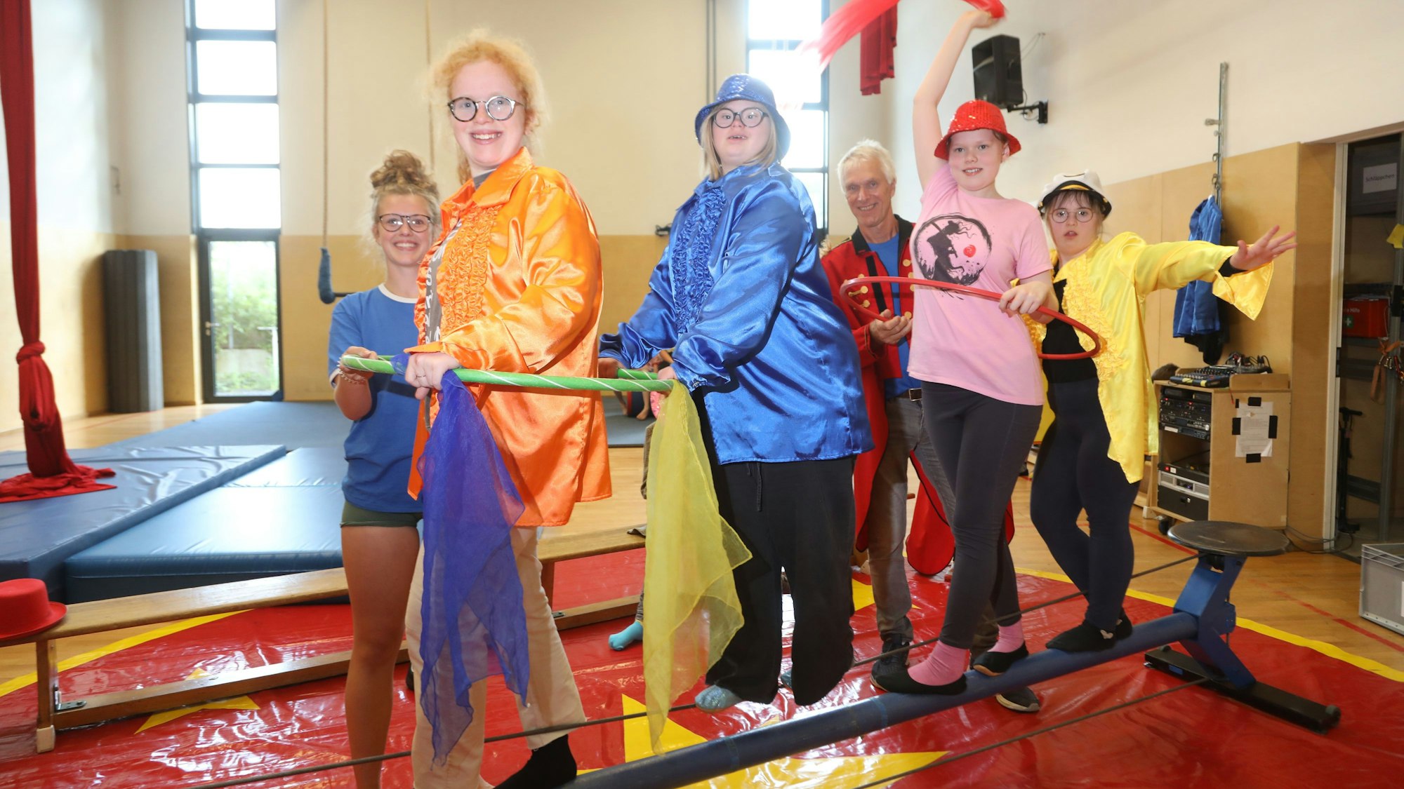 Vier junge Teilnehmerinnen des Zirkuskurses stehen auf einem Drahtseil, zwei von ihnen haben einen Hula-Hoop-Reif um den Bauch gelegt