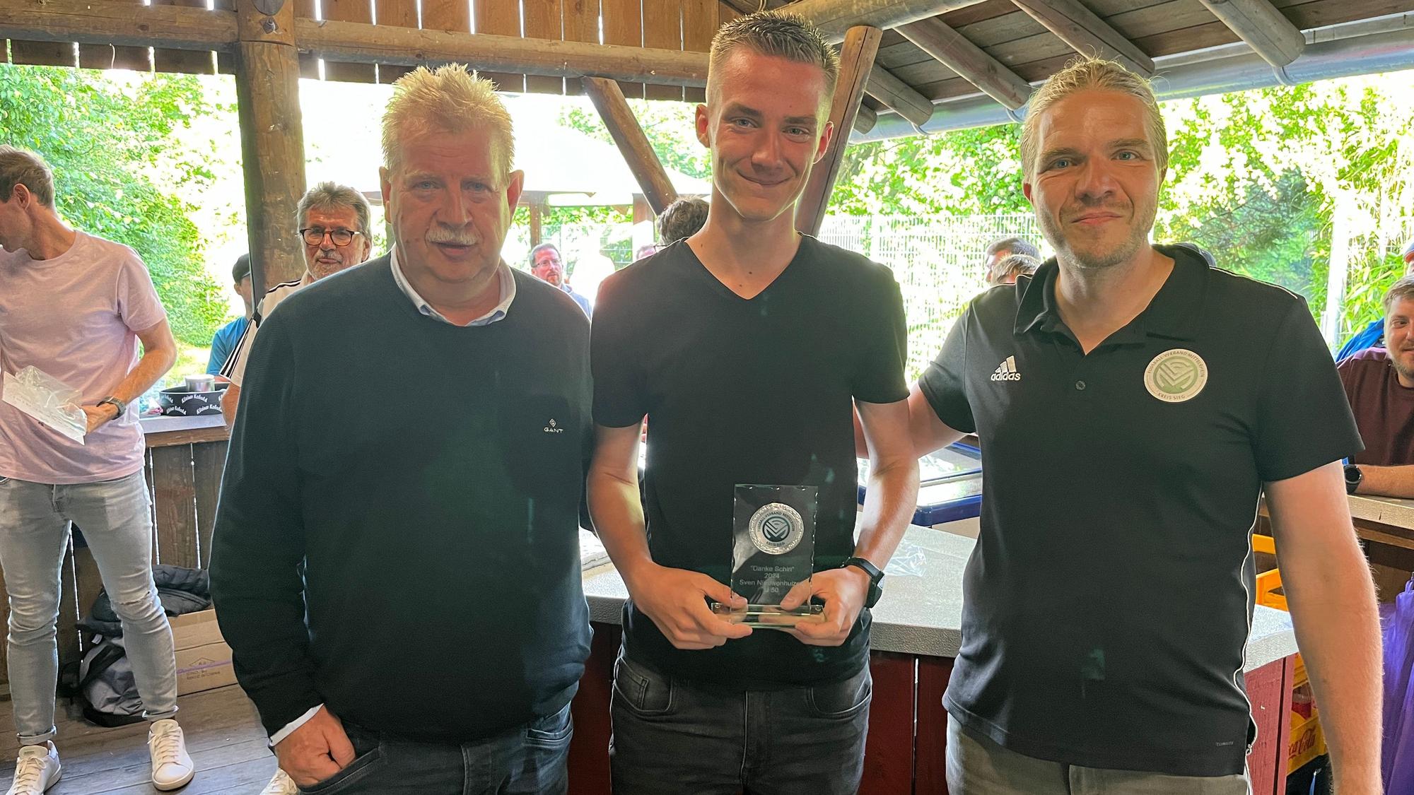 Guido Fuchs, Kreisvorsitzender, Sven Niewenhuizen, Sieger der DFB-Aktion "Danke Schiri" und Kreis-Schiri-Ausschuss-Vertreter Bernd Peters (v.l.) stehen in einer Grillhütte.