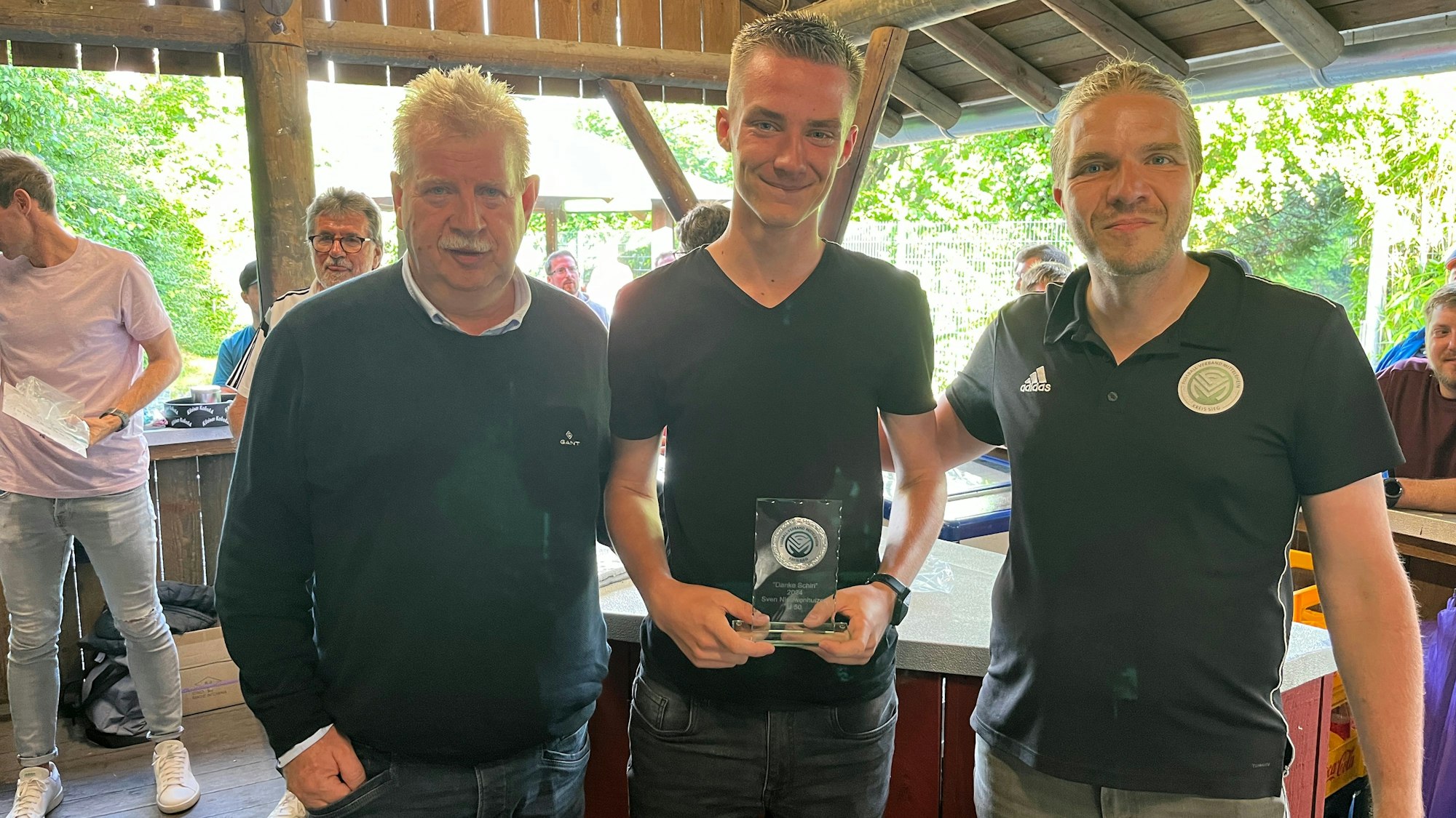Guido Fuchs, Kreisvorsitzender, Sven Niewenhuizen, Sieger der DFB-Aktion "Danke Schiri" und Kreis-Schiri-Ausschuss-Vertreter Bernd Peters (v.l.) stehen in einer Grillhütte.