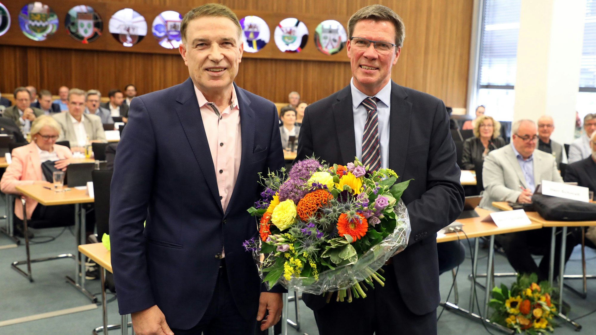 Ex-Kreisdirektor Dr. Erik Werdel und Landrat Stephan Santelmann stehen neben einander, der Landrat hält einen Blumenstrauß.