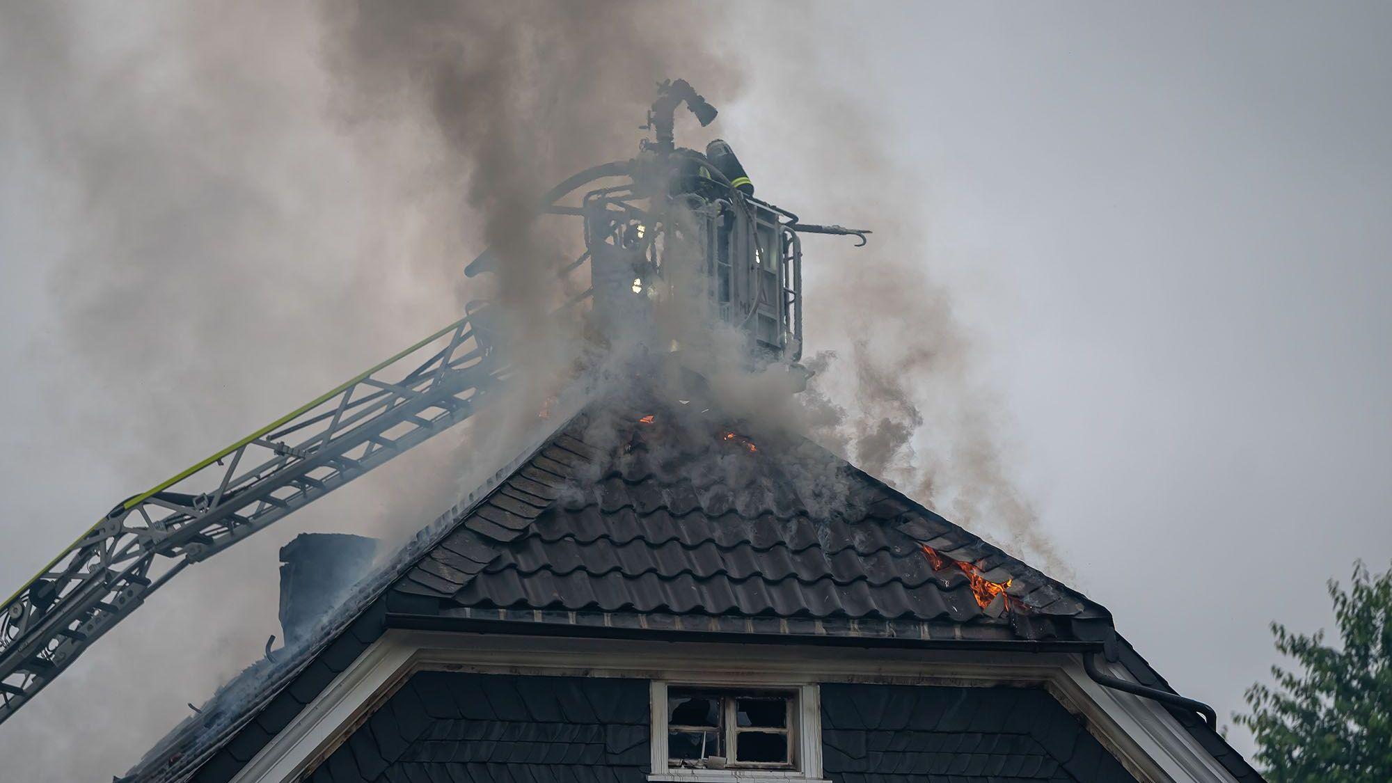 Von der Drehleiter aus bekämpfen Feuerwehrleute den Dachstuhlbrand in einem Mehrfamilienhaus in Gummersbach-Derschlag.
