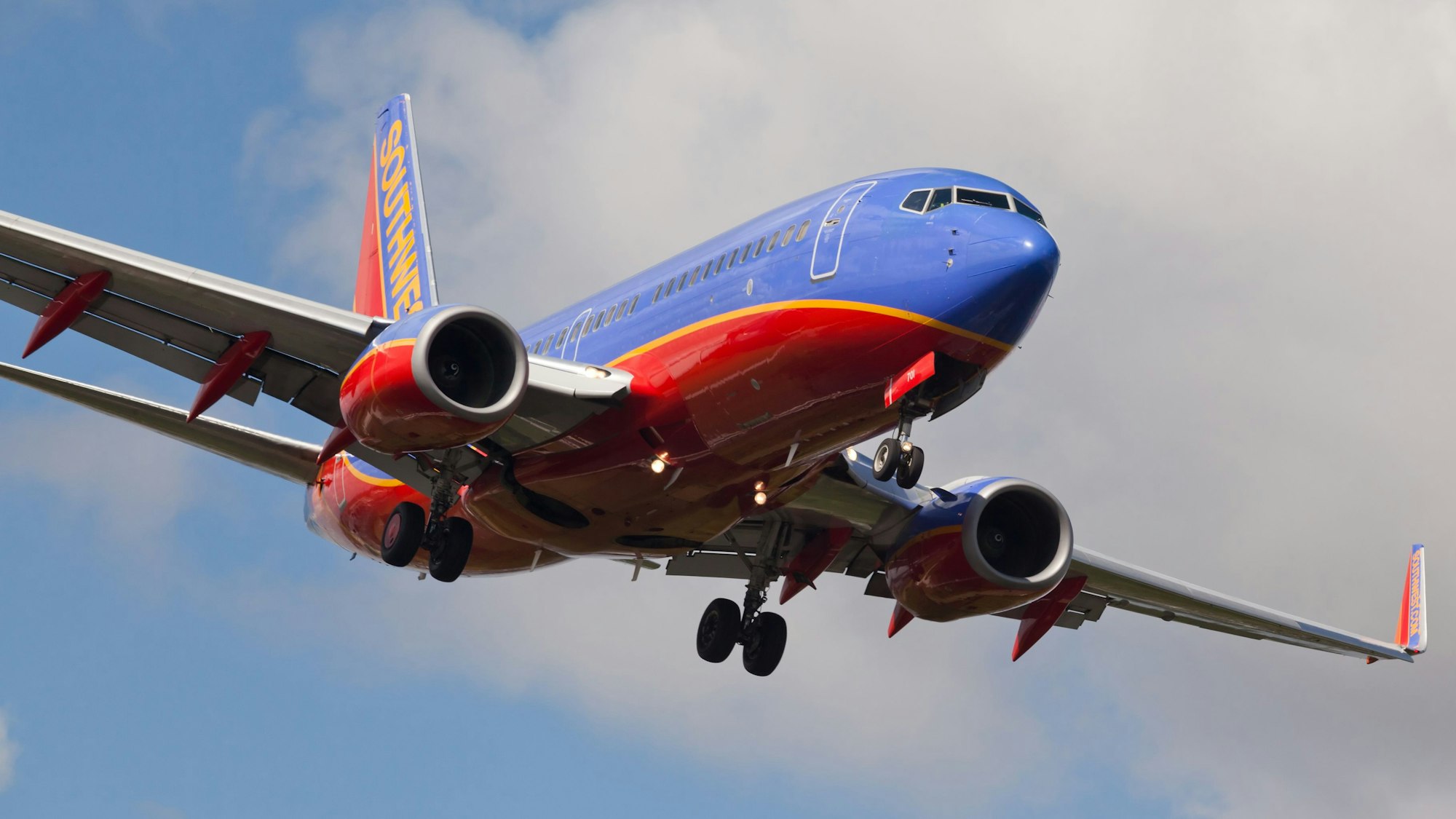 Eine Boeing 737 der US-Fluggesellschaft Southwest Airlines im Landeanflug auf einen Flughafen. Die Maschine ist markant in blau, rot und gelb lackiert. (Symbolbild).