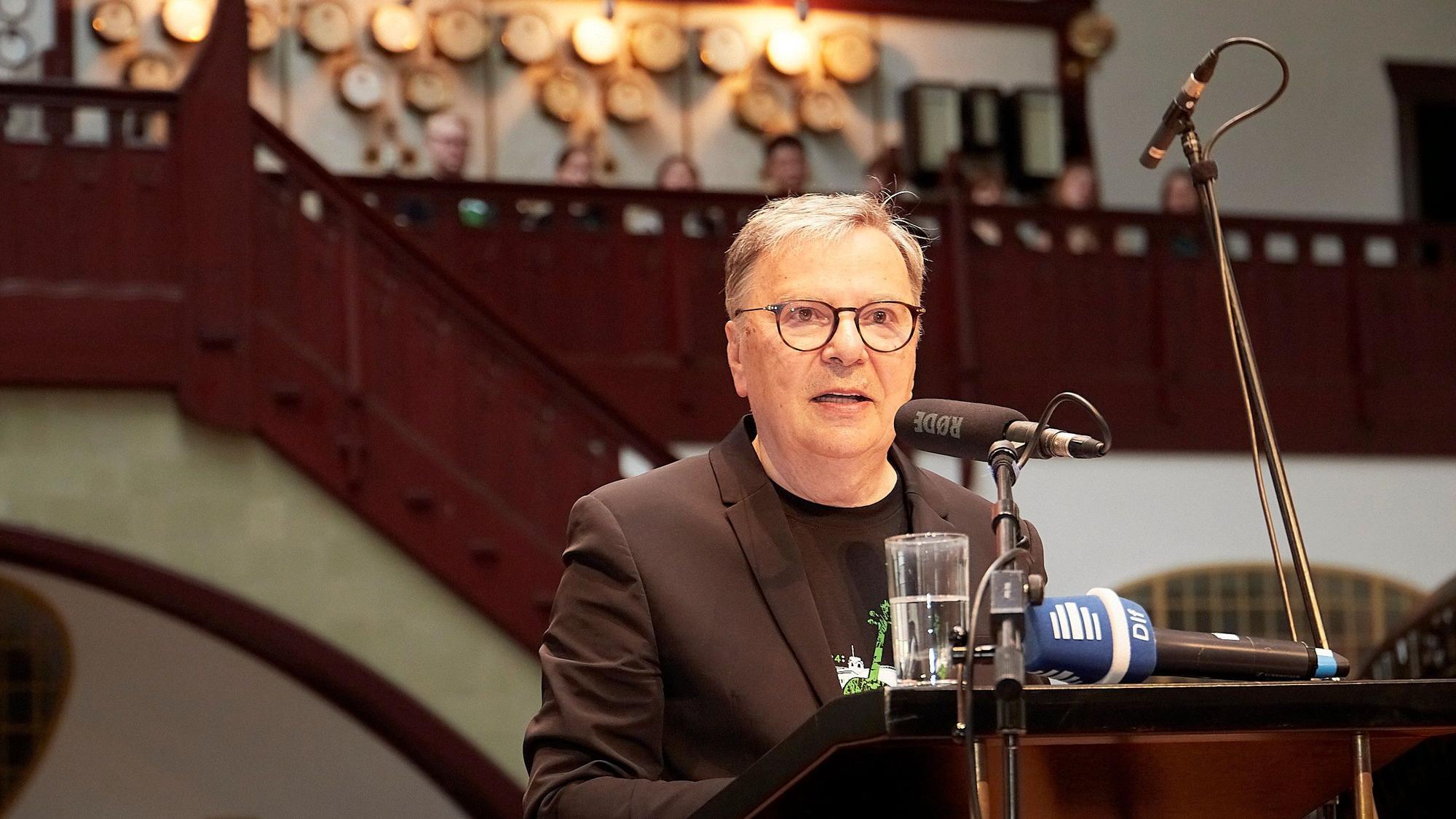Dr. Hans-Joachim Güttler steht an einem Mikrofon.