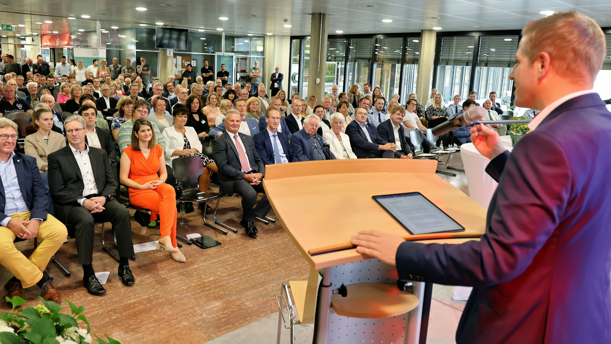 Landrat Markus Ramers steht an einem Pult und spricht zu einem großen Publikum.