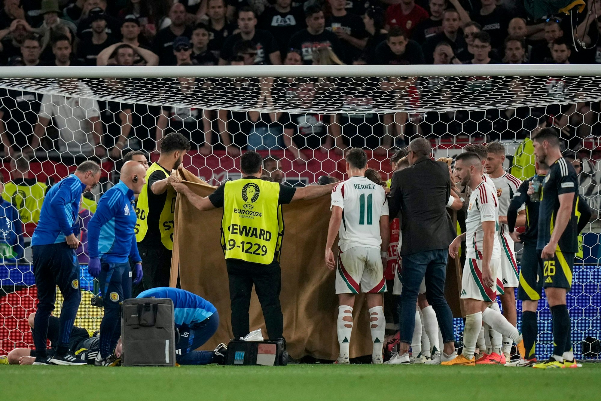 Stewards hold a blanket to protect the privacy of Hungary's Barnabas Varga as he gets medical treatment after a collision during a Group A match between Scotland and Hungary at the Euro 2024 soccer tournament in Stuttgart, Germany, Sunday, June 23, 2024. (AP Photo/Matthias Schrader)